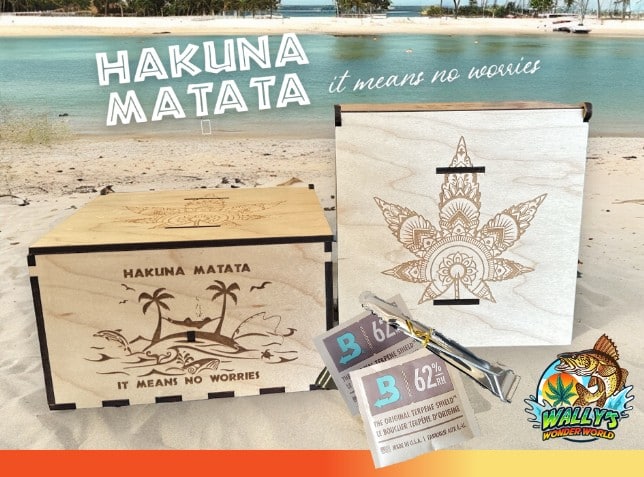Engraved wooden cannabis stash boxes reading Hakuna Matata and featuring a mandala leaf design on a sandy beach setting with Boveda humidity packs.